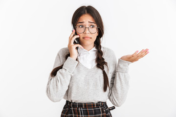 Canvas Print - Photo closeup of sad puzzled teenage girl wearing eyeglasses and school uniform expressing confusion while talking on smartphone