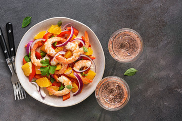 Ceviche with shrimps and orange, two glasses of pink sparkling wine, dark rustic background. Top view, copy space.