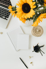 Wall Mural - Flatlay of home office desk workspace with laptop, notebook, yellow sunflowers bouquet on white background. Top view freelancer / blogger summer floral work concept.