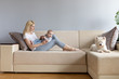 Young mother and child in her hands happy with white westie west highland white terrier dog on a white sofa with grey wallss miling and playng