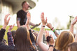 © Daniil - Fans clap their hands, raise hands and show rockers on an open-air air rock concert in front of a stage where professional musicians perform. Blurred guitarist.