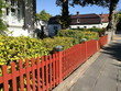 Frisch gestrichener rotbrauner Holzzaun vor einem grünen Vorgarten im Sommer bei Sonnenschein in der Detmolder Straße in Oerlinghausen am Hermannsweg im Teutoburger Wald in Ostwestfalen-Lippe