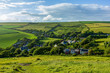 A view of a rural village (West Lulworth) from the hill under a majestic blue sky and some white clouds