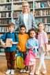 © LIGHTFIELD STUDIOS - attractive and cheerful woman in glasses standing with cute multicultural children in library