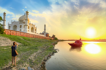 Fototapete - Taj Mahal scenic sunset view on the banks of river Yamuna with woman tourist enjoying the view