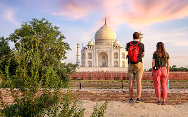 Fototapete - Tourist couple enjoy Taj Mahal sunset view  from Mehtab Bagh. Taj Mahal is a historic monument  built on the banks of river Yamuna at Agra India.
