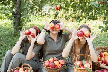 Girls with Apple in the Apple Orchard. Beautiful sisters with Organic Apple in the Orchard. Harvest Concept. Garden, teenagers eating fruits at fall harvest.