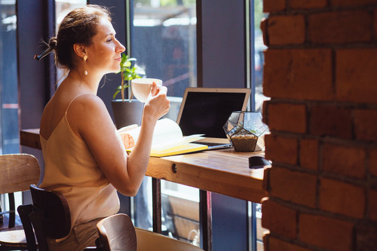 Female calligrapher dreaming in cafe. Portrait of mature business woman drinking coffee writing something in notebook. Calligraphy, lettering, graphic design handwriting, creation concept.
