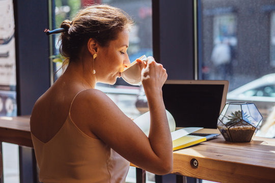 Female calligrapher dreaming in cafe. Portrait of mature business woman drinking coffee writing something in notebook. Calligraphy, lettering, graphic design handwriting, creation concept.