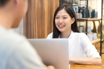 Wall Mural - Young Asian woman sitting in cafe talking and having a meeting.