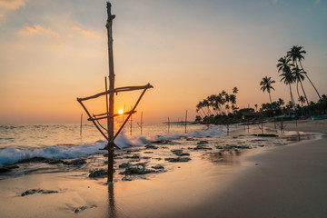 Wall Mural - Silhouettes of the traditional Sri Lankan stilt fishermen at the sunset in Weligama, Sri Lanka.