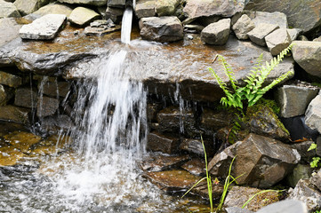 Wall Mural - Small waterfall among stones outdoors in nature.