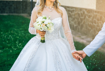 Wall Mural - Wedding couple in love is walking outdoors. Groom in blue suit and bride in luxury dress. Beautiful bouquet in hands.