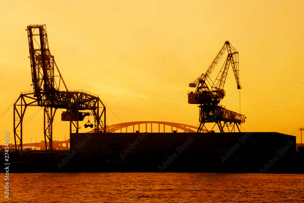 Silhouette of container crane at Osaka port are loading on evening with ...