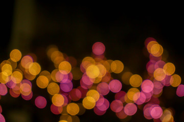 Wall Mural - Closeup abstract blurred and bokeh of reflection lighting of pink and yellow led light bubs on black background with copy space.