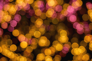 Wall Mural - Closeup abstract blurred and bokeh of reflection lighting of pink and yellow led light bubs on black background.