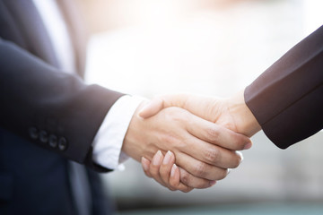 closeup of a businessman hand shake businesswoman between two colleagues ok, succeed in business hol