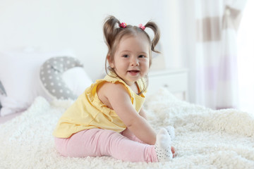 Wall Mural - Adorable little baby girl sitting on bed in room