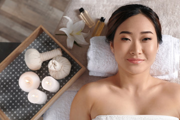 Wall Mural - Beautiful Asian woman lying on massage table in salon, top view