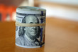 © jokerpro - financial image of close up rolled and rubber banded American one hundred dollar bills pile on desk
