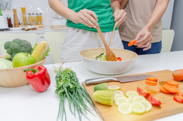 Diet. two young pretty woman in green shirt standing and preparing the vegetables salad in bowl for good healthy in modern kitchen at home, healthy lifestyle, cooking, healthy food and dieting concept