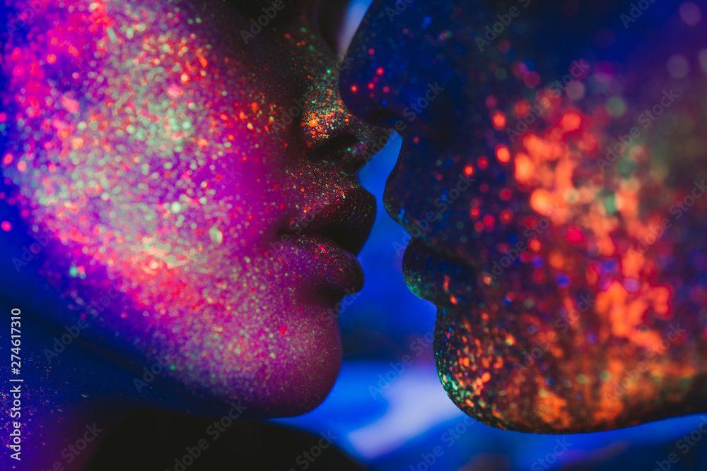 Couple kissing in the disco club with fluorescent paintings on the faces - obrazy, fototapety, plakaty 