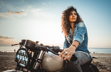 Beautiful Girl Having Fun Driving Her Custom Cafe Racer Motorcycle, Enjoying The Sunset On The Beach