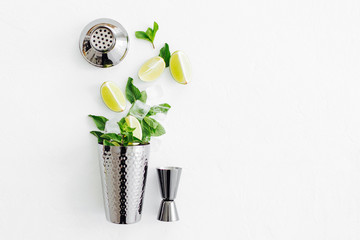 Set of bar accessories for cocktail making. Shaker, jigger, glass, spoon  and  other bar tools with lime and mint leaves on withe  background.