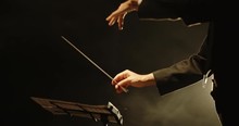 Close Up Shot Of Hands Of Symphony Orchesra Conductor Directing Music By Waving His Baton. Studio Shot On Black Background 4k Footage