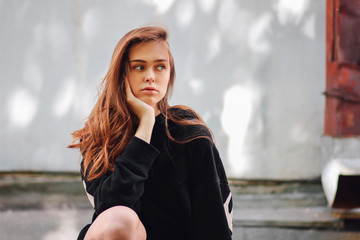 Candid portrait of young beautiful long hair girl fashion model hipster on city street