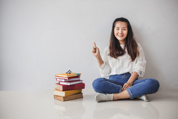 Education in high school university college concept, Young woman smiling happily sitting near a big books and glasses isolated on white background.