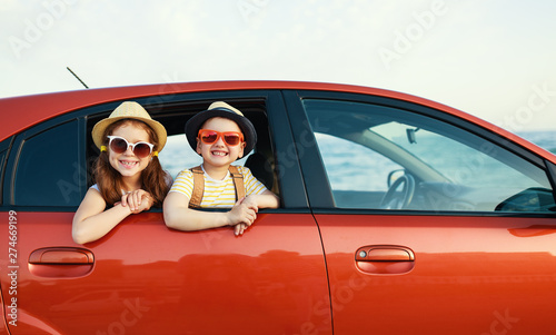 Fotomural happy children girl and boy goes to summer travel trip in car.