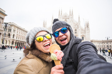 Travel in winter and relationship concept - Funny couple taking self portrait with ice-cream in Duomo square.