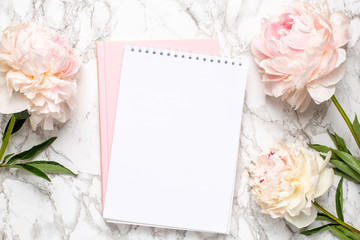 Beautiful white peony flower and notebook on marble background