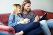 © nenetus - Lovely young couple drawing with they digital tablet while sitting on sofa at home.
