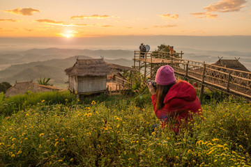 Woman photographer traveling and looking to beautiful view of the mountains range on Doi Sango (or Sa-Ngo) mountain in Chiang Saen district of Chiang Rai province of Thailand at sunrise.