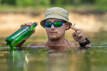 Portrait of a funny smoking a cigarette man, enjoying swimming in hat and sunglasses. Concept vacation, active rest