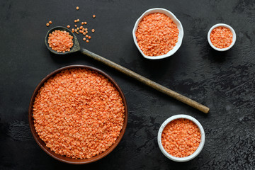 Wall Mural - Healthy dry grains red lentils or legume on black background. Top view