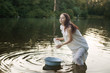 Young laundress in nightie washing clothes in the river.