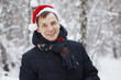 © olgasparrow - Young man in a Christmas hat is smiling in the winter forest.