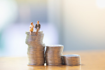 Business ,Finance and Saving Concept. Close up of businessman and woman sitting and talking on top of stack of silver coins.