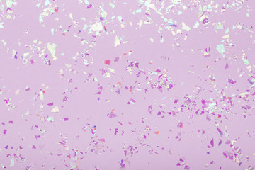 Wall Mural - Glowing mica sparkles on pastel violet trendy background. Festive abstract backdrop with confetti. Flat lay.