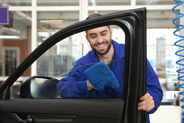 Canvas Print - Worker cleaning automobile window glass with rag at car wash