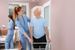 © New Africa - Nurse assisting senior patient with walker in hospital ward