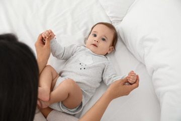 Poster - Cute baby playing with mother on bed, above view