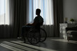 © New Africa - Young man sitting in wheelchair near window indoors