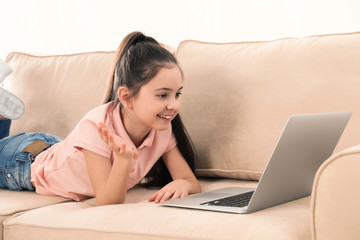 Wall Mural - Little girl using video chat on laptop at home