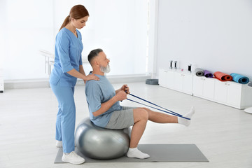 Sticker - Professional physiotherapist working with senior patient in rehabilitation center