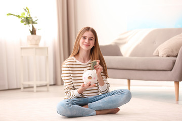 Poster - Teen girl with piggy bank and money at home