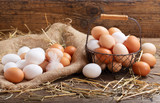 basket of colorful fresh eggs on wooden table